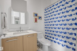 Bathroom featuring a light wood-finish vanity with a stone countertop, an undermount sink, and chrome fixtures - 
