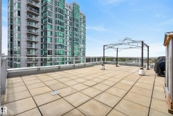 Expansive rooftop terrace featuring large square pavers and a metal gazebo frame - 