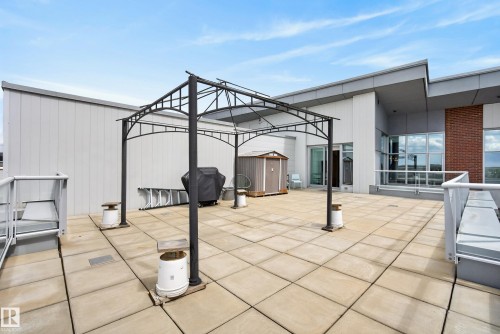 Spacious rooftop patio featuring concrete paver flooring, a black metal pergola, and a visible storage shed - 808 2612 109 Street, Edmonton, AB - Outdoor With Exterior