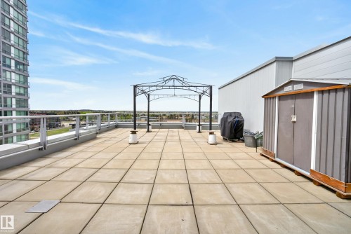 Expansive rooftop patio featuring large format paver flooring, a perimeter glass railing system, and a decorative metal pergola frame - 808 2612 109 Street, Edmonton, AB - Outdoor With Exterior