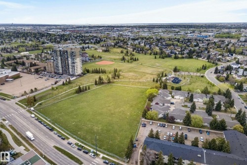Expansive green spaces and mature trees surround this residential area featuring a multi-story building, townhomes, and a commercial parking lot - 808 2612 109 Street, Edmonton, AB - Outdoor With View