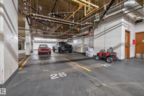 Underground parking garage featuring concrete pillars, painted floor markings, exposed ceiling pipes, and fluorescent strip lighting - 808 2612 109 Street, Edmonton, AB - Indoor Photo Showing Garage