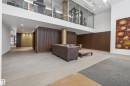 Lobby area featuring a mezzanine-level fitness center with glass paneling, recessed lighting, wood-paneled walls, and light-toned flooring - 808 2612 109 Street, Edmonton, AB  - Indoor Photo Showing Other Room 
