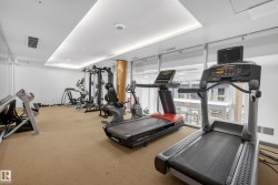 Fitness room featuring cardio equipment, strength training machines, ample natural light from floor-to-ceiling windows, recessed lighting, and textural column accents - 