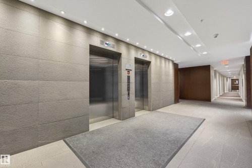 Elevator lobby featuring two stainless steel elevators, textured wall panels, recessed ceiling lighting, a grey floor mat, and tile flooring - 808 2612 109 Street, Edmonton, AB - Indoor Photo Showing Other Room