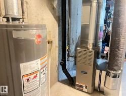 Rheem Performance water heater and Carrier furnace, featuring a power vent system and ductwork, set against a concrete wall - 