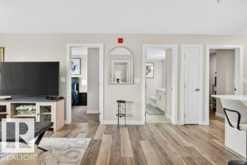 Warm wood-finish flooring extending through an open living area - 209 1029 173 Stnw, Edmonton, AB - Indoor