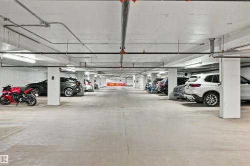 Underground parking garage featuring concrete flooring, exposed utility piping, and fluorescent lighting - 209 1029 173 Stnw, Edmonton, AB - Indoor Photo Showing Garage