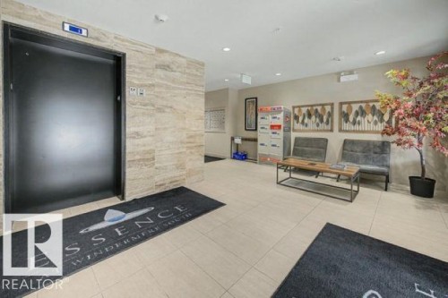 Lobby featuring an elevator with a black door, light tile flooring, and a stone-look accent wall - 209 1029 173 Stnw, Edmonton, AB - Indoor Photo Showing Other Room
