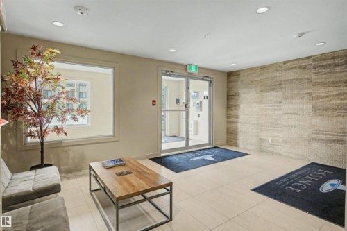 Lobby featuring large format tile flooring, a textured accent wall, recessed lighting, and expansive windows - 209 1029 173 Stnw, Edmonton, AB - Indoor