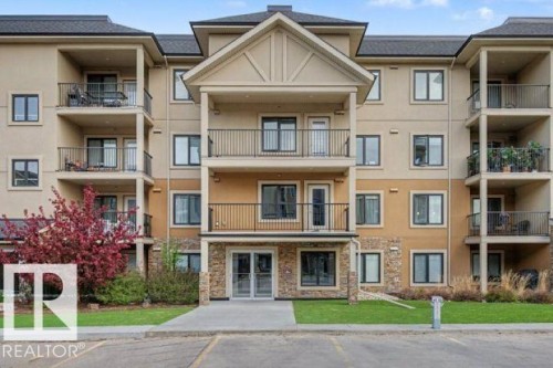 Multi-story building featuring tan and brown stucco siding with stone veneer accents - 209 1029 173 Stnw, Edmonton, AB - Outdoor With Balcony With Facade