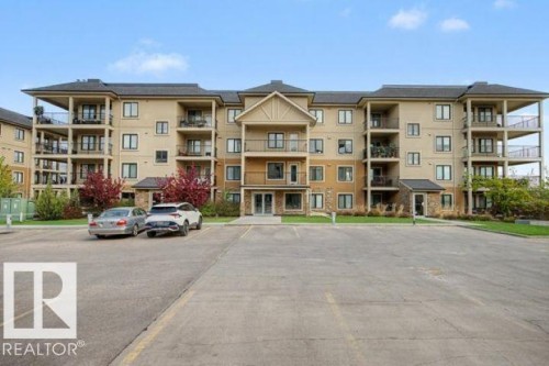 Multi-story building featuring tan stucco and stone façade - 209 1029 173 Stnw, Edmonton, AB - Outdoor With Balcony With Facade