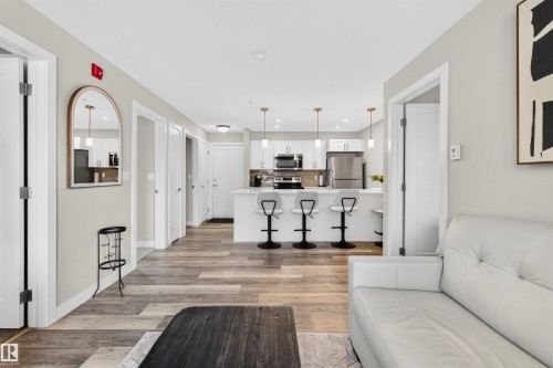 Open-concept living space featuring wood-finish flooring, recessed lighting, and a neutral wall palette - 209 1029 173 Stnw, Edmonton, AB - Indoor