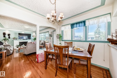 Dining area featuring wood-finish flooring, a multi-light chandelier, and a window with green trim - 11309 115 Street, Edmonton, AB - Indoor Photo Showing Dining Room