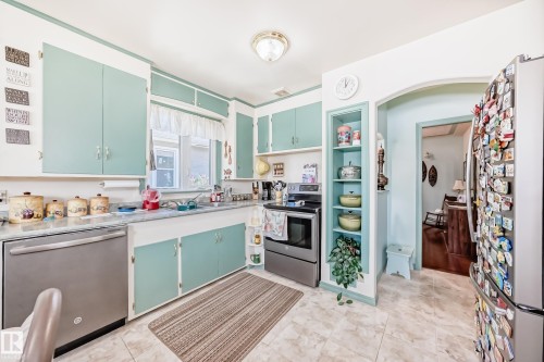 Kitchen featuring light blue cabinetry, stainless steel dishwasher, tile flooring, and an arched doorway - 11309 115 Street, Edmonton, AB - Indoor Photo Showing Kitchen