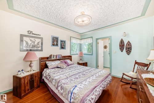 Hardwood flooring extends throughout this room, featuring a textured ceiling and a built-in headboard - 11309 115 Street, Edmonton, AB - Indoor Photo Showing Bedroom