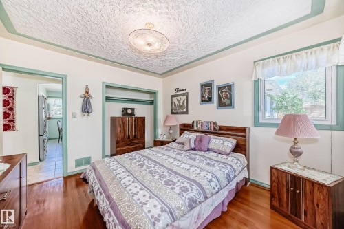 Well-lit room featuring rich wood-finish flooring, a detailed ceiling light fixture, and a window with natural light - 11309 115 Street, Edmonton, AB - Indoor Photo Showing Bedroom