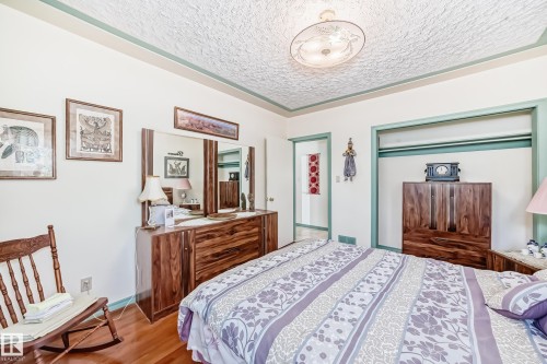 Bedroom featuring wood-finish flooring, a decorative ceiling light fixture, and an open closet space - 11309 115 Street, Edmonton, AB - Indoor Photo Showing Bedroom