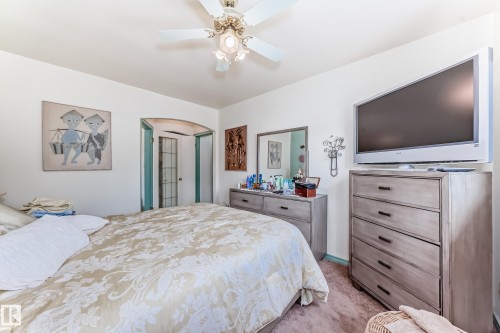 Bedroom featuring an arched doorway, ceiling fan, and wall-mounted light fixture - 11309 115 Street, Edmonton, AB - Indoor Photo Showing Bedroom