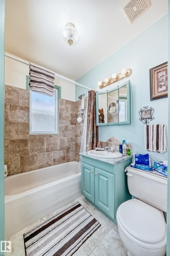 Full bathroom featuring a tub/shower combination with tile surround, a vanity with a white basin sink, a wall-mounted medicine cabinet, and a five-light fixture - 11309 115 Street, Edmonton, AB - Indoor Photo Showing Bathroom