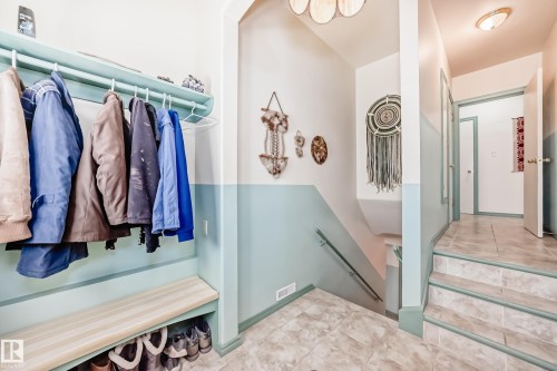 Entryway featuring tile flooring, built-in coat rack, built-in bench with shoe storage, and a staircase with a handrail - 11309 115 Street, Edmonton, AB - Indoor With Storage
