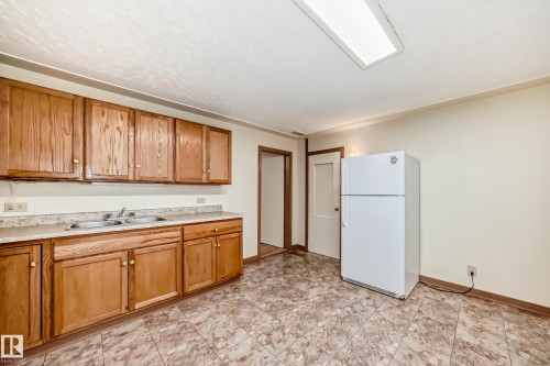 Kitchen featuring wood cabinetry, a double basin sink, laminate countertops, and patterned floor tiling - 11309 115 Street, Edmonton, AB - Indoor Photo Showing Kitchen With Double Sink