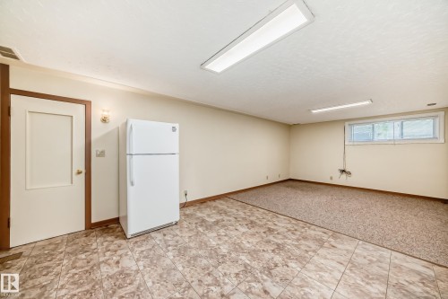 Spacious room featuring mixed flooring with patterned tile and carpeting, neutral wall tones, and overhead fluorescent lighting - 11309 115 Street, Edmonton, AB - Indoor