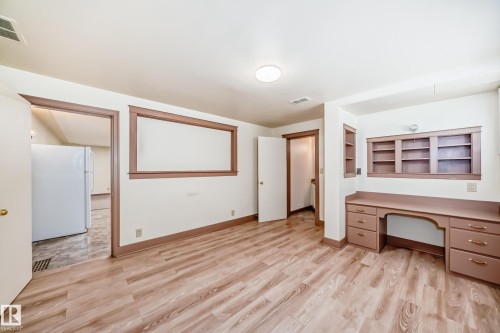 Room featuring wood-finish flooring, built-in desk cabinetry, and integrated shelving - 11309 115 Street, Edmonton, AB - Indoor Photo Showing Other Room