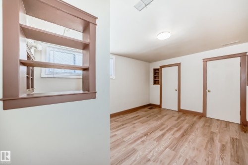 Room featuring wood-finish flooring, white walls, and two white doors with contrasting trim - 11309 115 Street, Edmonton, AB - Indoor Photo Showing Other Room