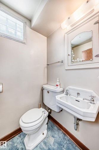 Compact bathroom featuring a wall-mounted sink, a toilet, an overhead light fixture, and a glass block window - 11309 115 Street, Edmonton, AB - Indoor Photo Showing Bathroom