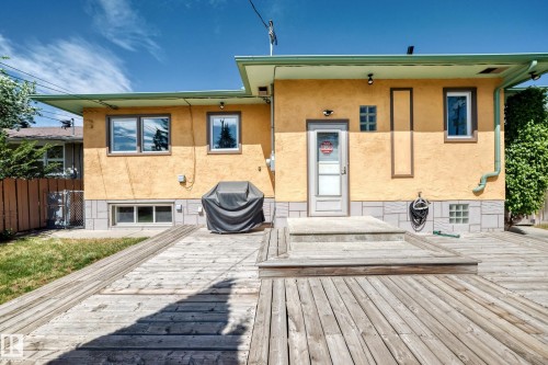 Expansive wood-finish decking featuring a ramp and steps leading to a rear exterior door - 11309 115 Street, Edmonton, AB - Outdoor With Deck Patio Veranda