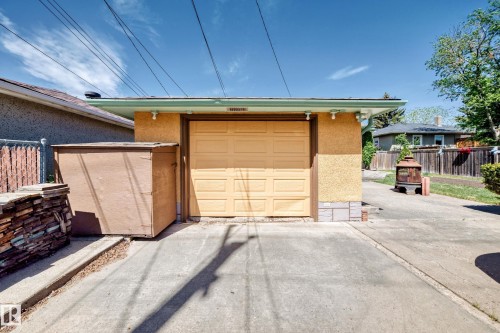 Detached garage featuring a paneled door, stucco exterior, and concrete driveway - 11309 115 Street, Edmonton, AB - Outdoor With Exterior