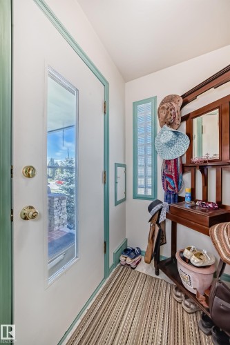 Entryway featuring a white door with a vertical window pane, teal trim, and a patterned area rug - 11309 115 Street, Edmonton, AB - Indoor