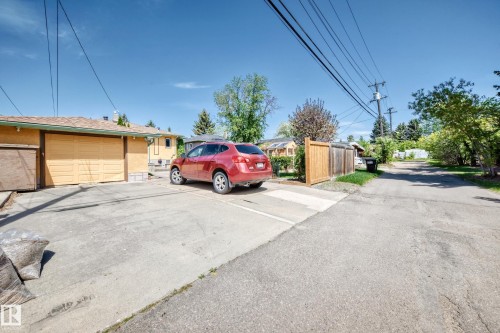 Detached garage with a paneled door, concrete driveway, wood privacy fence, and mature trees - 11309 115 Street, Edmonton, AB - Outdoor