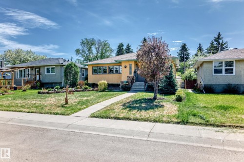 Single-story residence featuring a yellow stucco exterior, stone facade accents, and a front entry with concrete steps - 11309 115 Street, Edmonton, AB - Outdoor With Facade