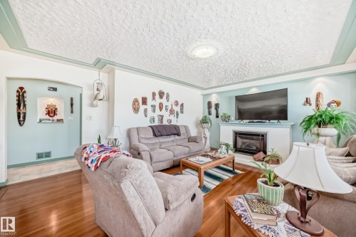 Living area featuring wood-finish flooring, a white mantel fireplace, and recessed lighting - 11309 115 Street, Edmonton, AB - Indoor Photo Showing Living Room With Fireplace