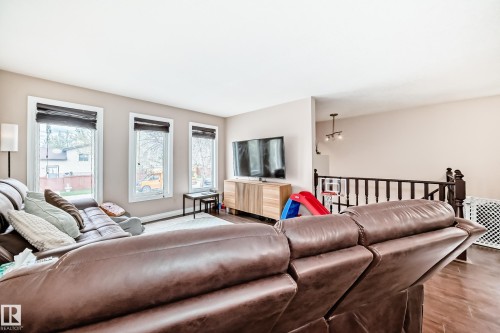 Living area with wood-finish flooring and three white-trimmed windows - 9110 180A Avenue, Edmonton, AB - Indoor Photo Showing Living Room