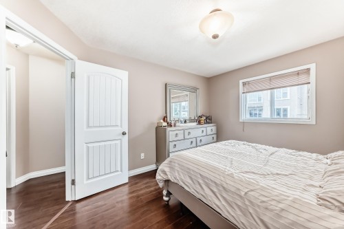 Bedroom featuring rich wood-finish flooring, a white paneled door, and a single window with blinds - 9110 180A Avenue, Edmonton, AB - Indoor Photo Showing Bedroom