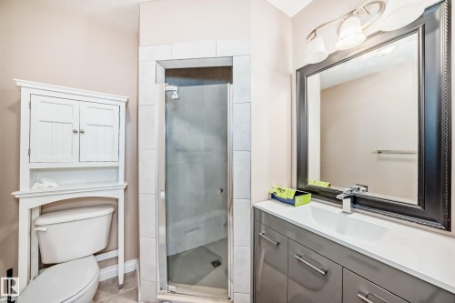 Bathroom featuring a glass-enclosed shower, a vanity with a white countertop and gray cabinetry, a rectangular mirror with a dark frame, and a white toilet - 9110 180A Avenue, Edmonton, AB - Indoor Photo Showing Bathroom