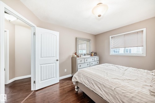 Spacious room featuring wood-finish flooring, a contemporary ceiling light fixture, and a window with blinds - 9110 180A Avenue, Edmonton, AB - Indoor Photo Showing Bedroom
