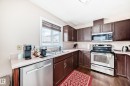 Kitchen featuring dark wood-finish cabinetry, light countertops, and stainless steel appliances - 9110 180A Avenue, Edmonton, AB  - Indoor Photo Showing Kitchen With Double Sink 