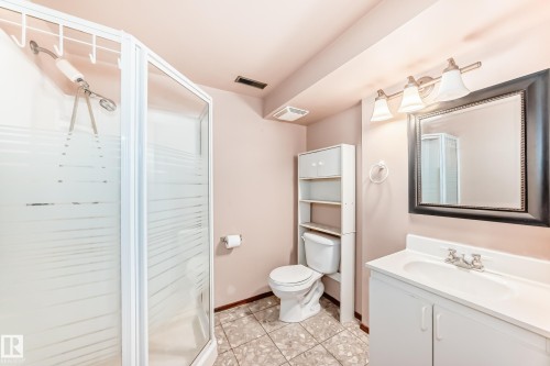 Full bathroom featuring a glass-enclosed shower with frosted accents, a vanity with a white countertop and base, a framed wall mirror, overhead three-bulb vanity lighting, and tiled flooring - 9110 180A Avenue, Edmonton, AB - Indoor Photo Showing Bathroom