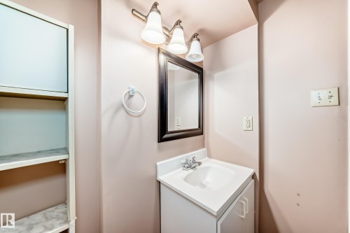 Bathroom vanity featuring a white countertop with integrated sink, chrome faucet, and a wall-mounted mirror with dark frame - 9110 180A Avenue, Edmonton, AB - Indoor Photo Showing Bathroom