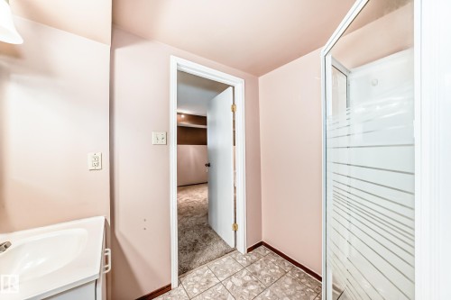Bathroom featuring a walk-in shower with frosted glass, tiled flooring, and a vanity with an integrated sink - 9110 180A Avenue, Edmonton, AB - Indoor Photo Showing Bathroom