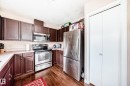 Kitchen featuring wood-finish flooring, dark wood cabinetry, light countertops, and stainless steel appliances including a refrigerator, range, and microwave - 9110 180A Avenue, Edmonton, AB  - Indoor Photo Showing Kitchen 