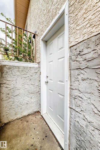 White paneled exterior door with brushed metal hardware, set into a textured stucco wall - 9110 180A Avenue, Edmonton, AB - Outdoor