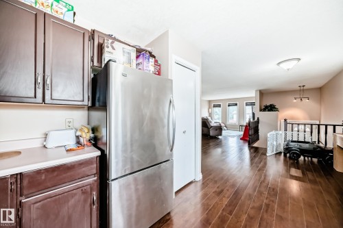 Kitchen area with wood-finish flooring, dark wood cabinetry, light countertops, and a built-in stainless steel refrigerator - 9110 180A Avenue, Edmonton, AB - Indoor