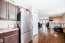 Kitchen area with wood-finish flooring, dark wood cabinetry, light countertops, and a built-in stainless steel refrigerator - 9110 180A Avenue, Edmonton, AB  - Indoor 