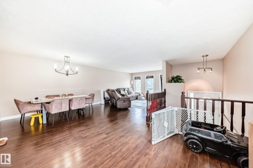 Spacious open-concept living area featuring rich wood-finish flooring, light neutral wall tones, and recessed lighting - 9110 180A Avenue, Edmonton, AB - Indoor