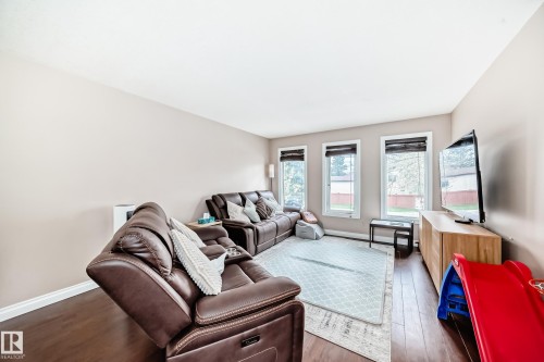 Inviting living space featuring wood-finish flooring, light-toned walls, and multiple windows with blinds - 9110 180A Avenue, Edmonton, AB - Indoor Photo Showing Living Room